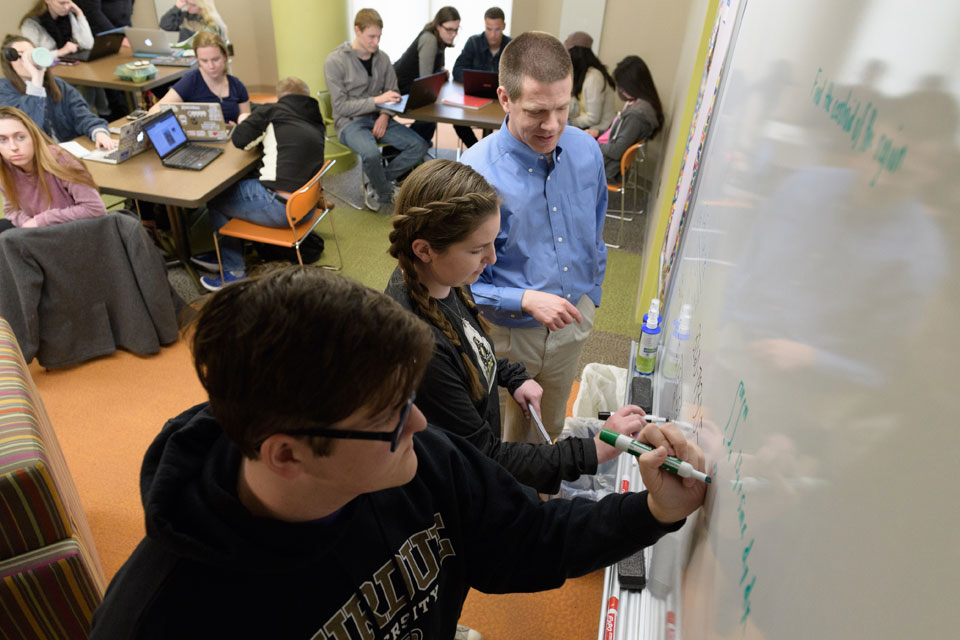 Students in the Data Mine work at a whiteboard alongside an instructor