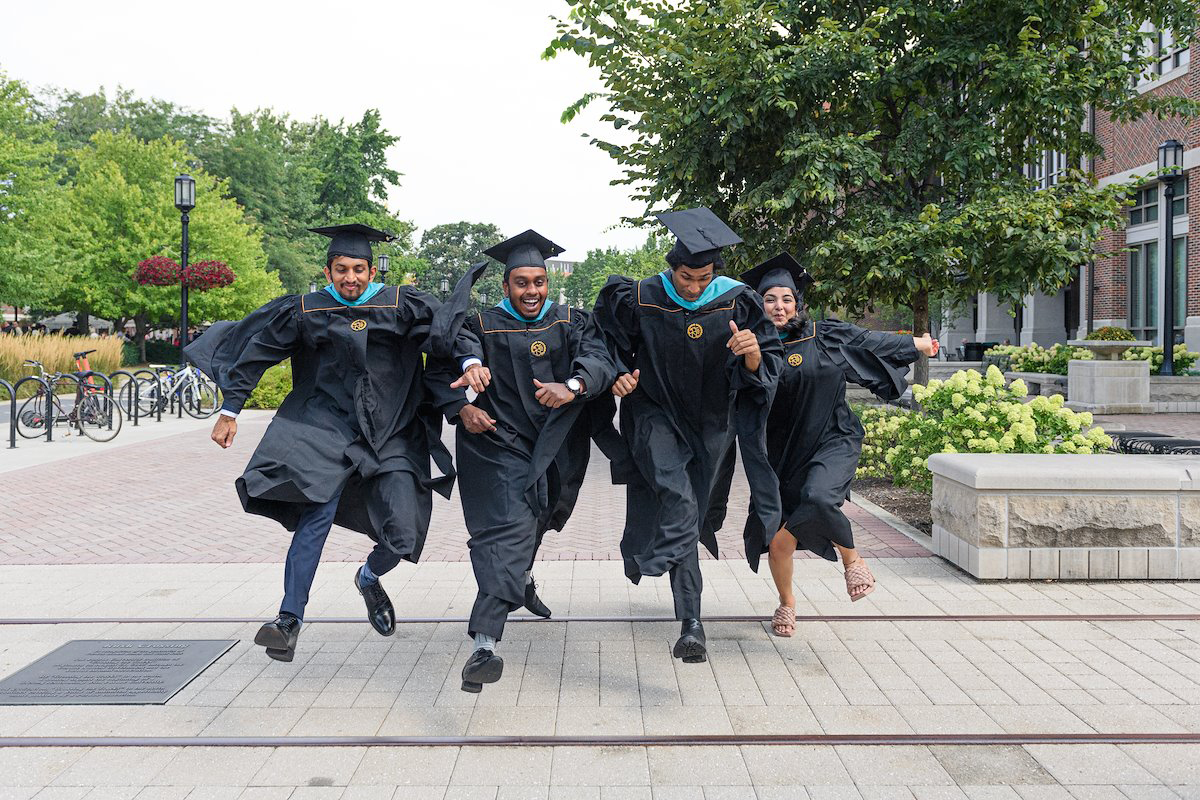 Four Purdue graduates make their traditional leap over the train tracks